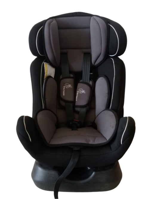 Black and gray car seat on a beige floor with a white wall background